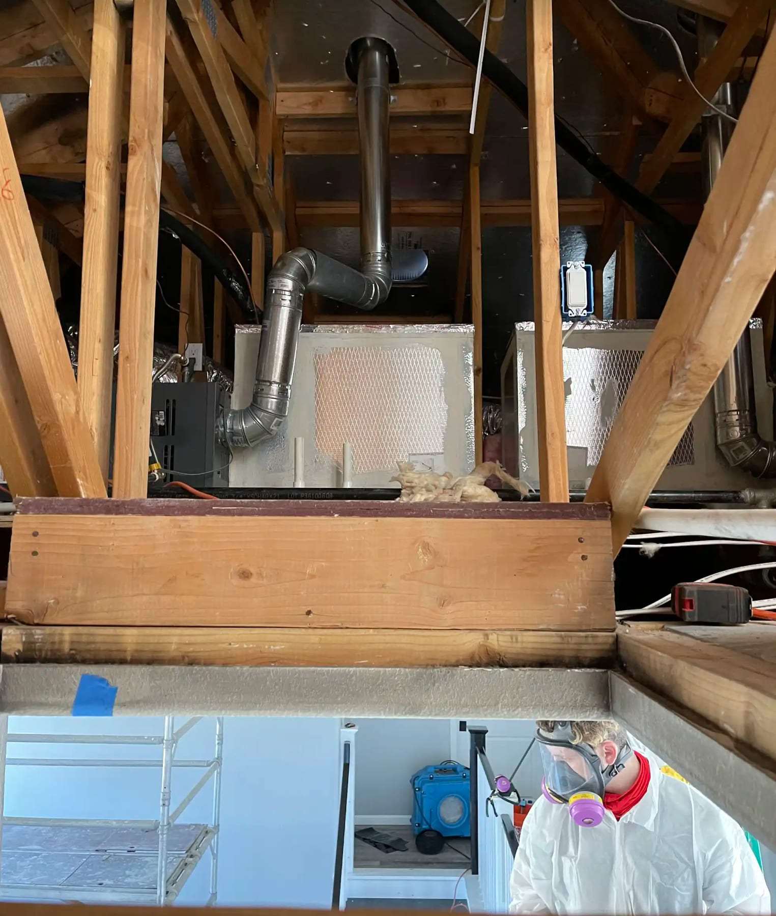 Attic framing and ductwork seen from the room below through an opened ceiling