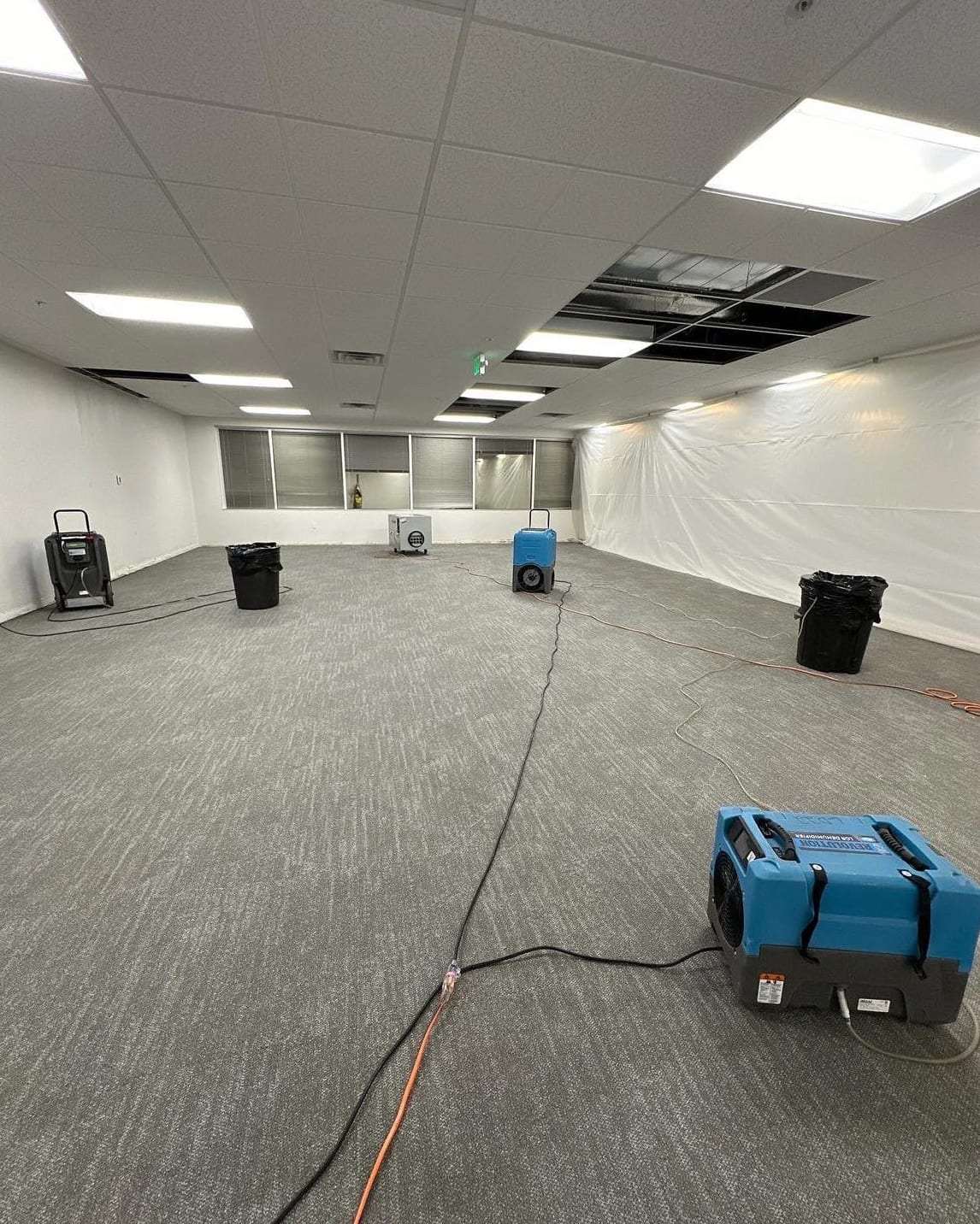 Empty office with dehumidifiers drying the carpet after a leak