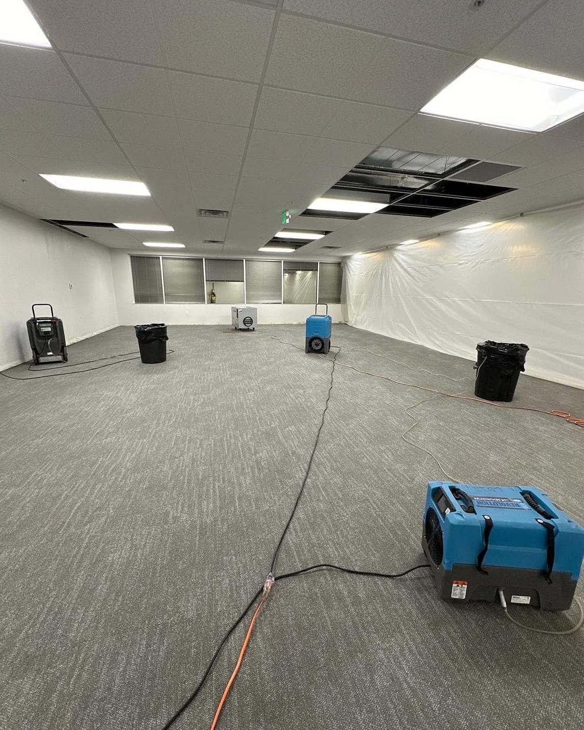 Empty office with dehumidifiers drying the carpet after a leak