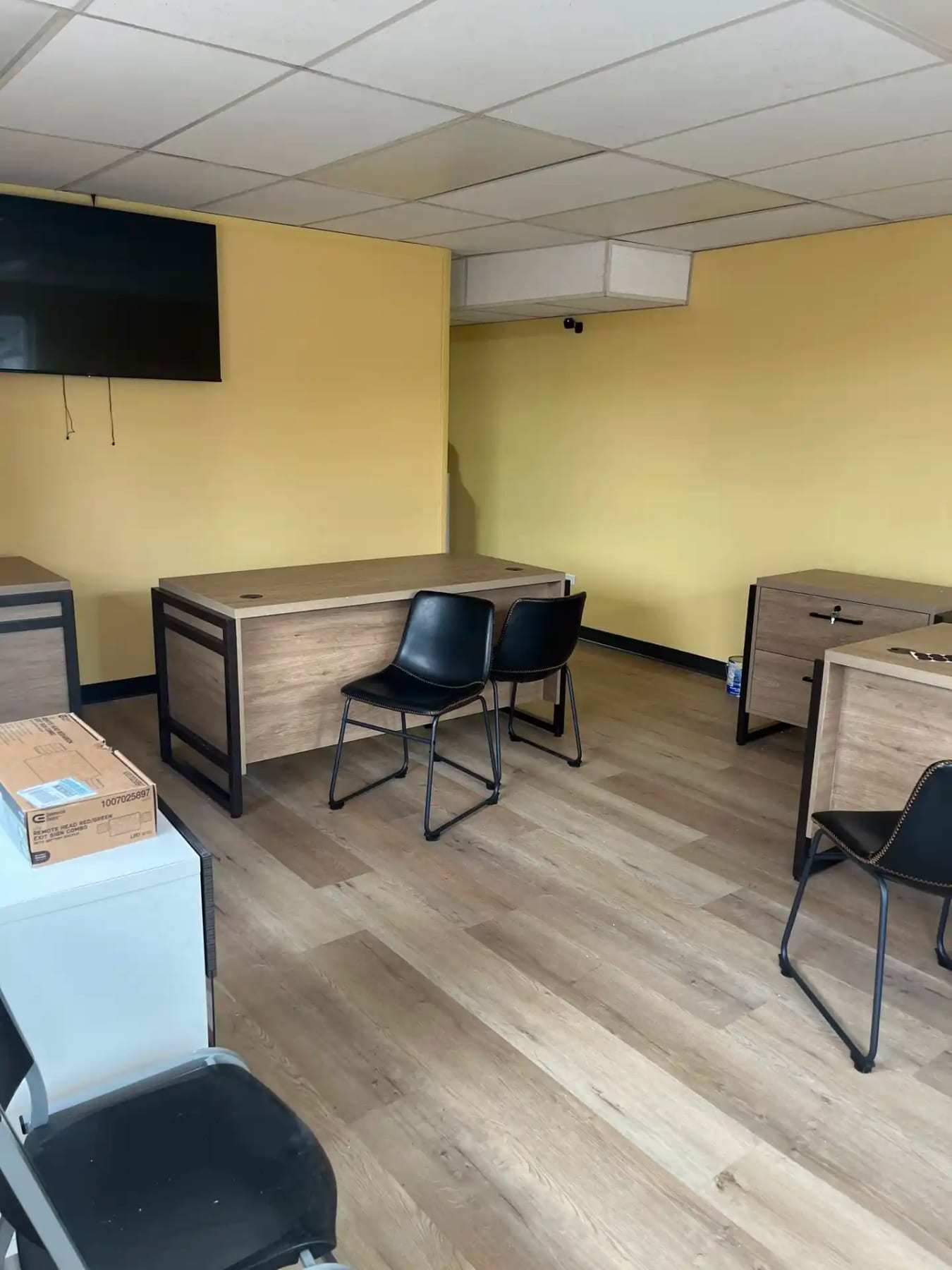 Small office with desks and chairs on plank flooring